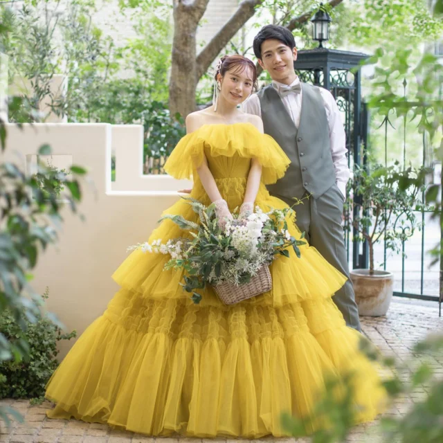 『Sachiko Tsutsui 』
⁡
@oiseaubleu_kochi の白と緑を基調とした背景にイエロードレスとタキシードのグリーンが映えます。
ヘッドドレスにはリボンを付け可愛らしい要素もプラス♪

ST0018 yellow

目を引く大人っぽいカラーにたっぷりのフレアーチュールフリルと、斬新な凸凹プリーツのティアードスカートが素敵な一着です。
胸元のフリルは取り外し可能で、オフショルダーにしたり、ビスチェにして背中に羽の様にフリルを流したり、自分好みにアレンジを楽しんでいただけるのも魅力の一つです。

気になるドレスがございましたら、
保存をタップ！ひよしやスタイリストにお見せください^_^

Tel. 088-882-9611
HP. www.hiyoshiya.co.jp
( ページ上部URLから飛んで頂けます )

・
#サチコツツイ#ST
#ウェディング#ウェディングドレス#白ドレス#カラードレス #運命の一着#ドレス迷子#ドレス選び#花嫁#結婚式#結婚準備#結婚式準備#プレ花嫁#ドレスショップ#ウェディングドレス試着 #高知#高知婚#高知ウェディング#高知ウエディング#高知ウェディングドレス#高知ウェディングフォト#高知ドレスショップ#高知結婚式#高知結婚式場 #ひよしや#hiyoshiya#weddingdress#colordress  #ひよしや高知